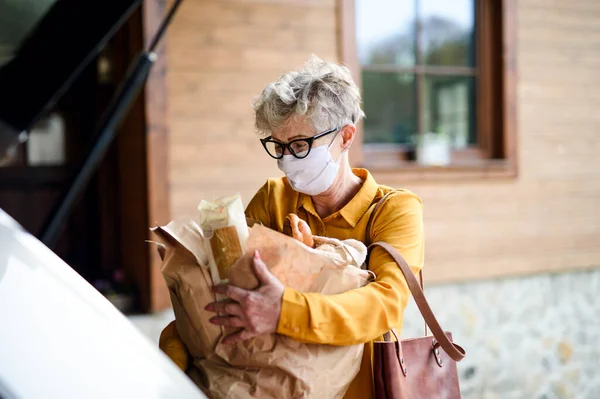 Старшая женщина в маске на открытом воздухе с покупками, коронным вирусом и карантинной концепцией . — стоковое фото