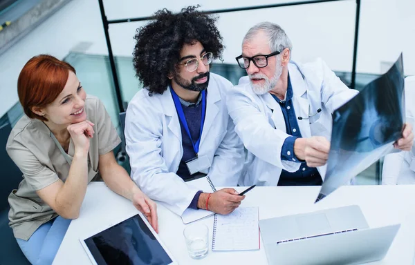 Ärztegruppe betrachtet Röntgenbild auf medizinischer Konferenz und diskutiert Fragen. — Stockfoto