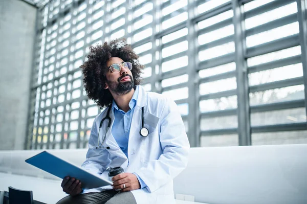 Porträtt av manlig läkare med urklipp sitter på sjukhus. Kopiera utrymme. — Stockfoto
