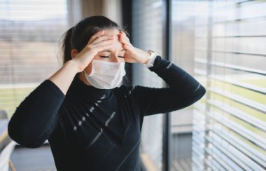 Evde baş ağrısı ve yüz maskeleri olan bir kadın, Corona virüsü konsepti..
