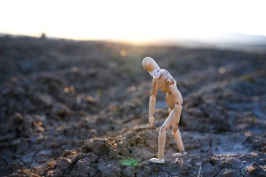 Kuru toprakta yüzü maskeli yorgun ahşap manken, korona virüsü, ölüm ve yaşam konsepti.