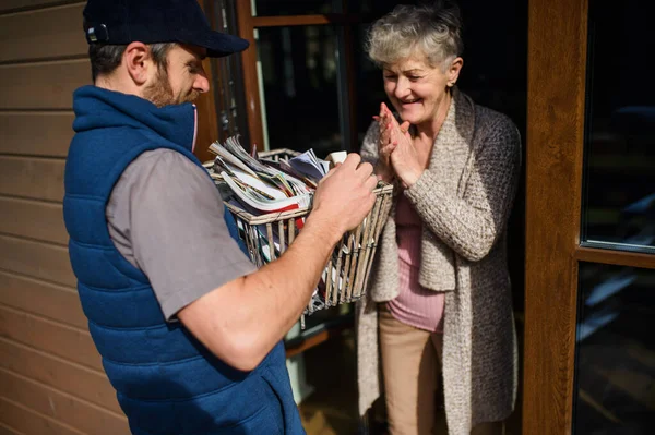 Uomo corriere consegna libri e riviste alla donna anziana . — Foto Stock