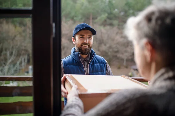 Man courier delivering parcel box to senior woman. — Stock Photo, Image