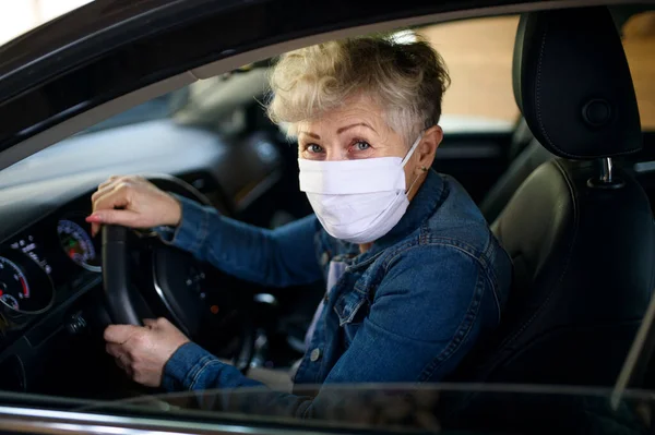Старшая женщина-водитель в маске в машине, концепция карантина . — стоковое фото