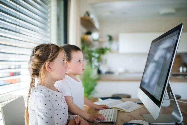 Liten flicka och pojke använder dator inomhus hemma. Begreppet koronavirus och karantän. — Stockfoto