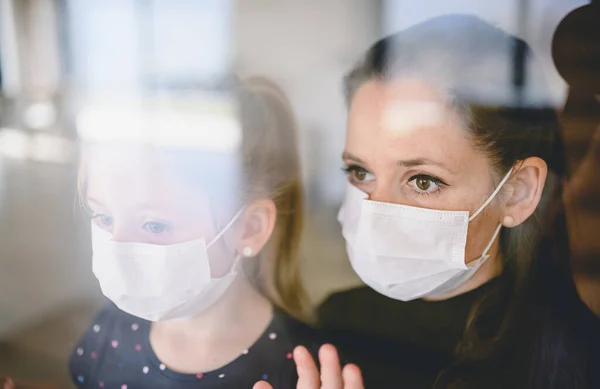 집안에서 마스크를 쓰고 있는 어머니와 자녀, 코로나 바이러스와 검역 개념. — 스톡 사진