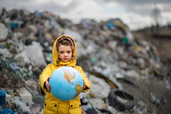 Small child holding globe on landfill, environmental pollution concept. — Stock Photo, Image