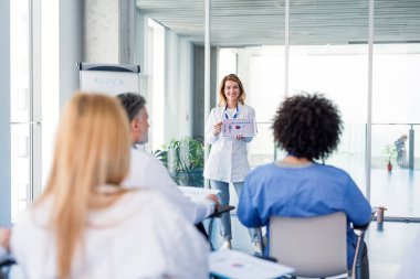 Bir grup doktor konferansta, tıbbi ekip oturuyor ve sunumu dinliyor..