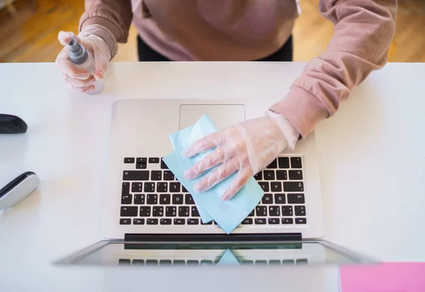 Onherkenbare jonge student met handschoenen aan tafel, ontsmettende laptop. — Stockfoto