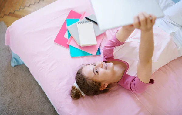 Menina com tablet sentado na cama, relaxante durante a quarentena . — Fotografia de Stock