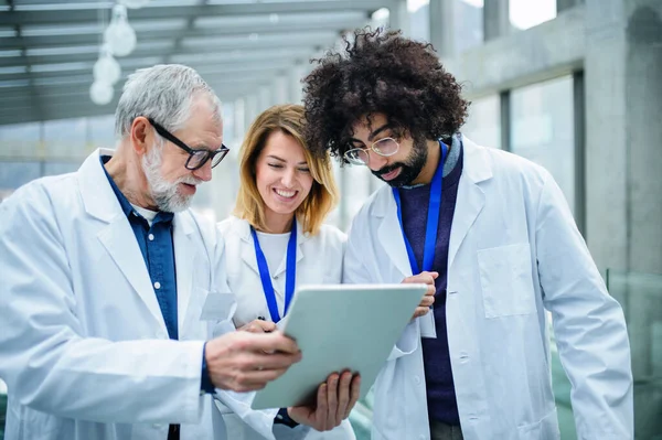 Ärztegruppe mit Tablet auf Konferenz, medizinisches Team diskutiert Fragen. — Stockfoto