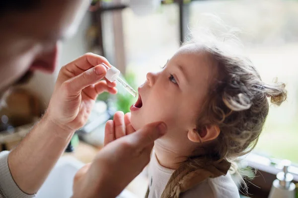 Padre irriconoscibile che dà gocce a piccola figlia malata in casa . — Foto Stock