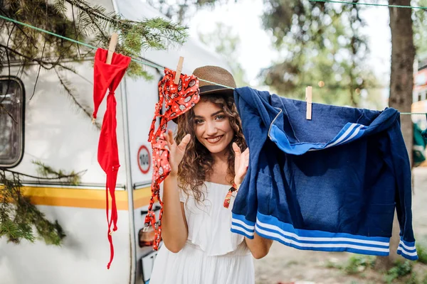 Kamp yapan genç bir kadın, çamaşır ipine elbise asıyor.. — Stok fotoğraf