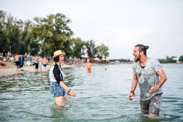 Pareja joven parada en el lago en el festival de verano, divirtiéndose . — Foto de Stock