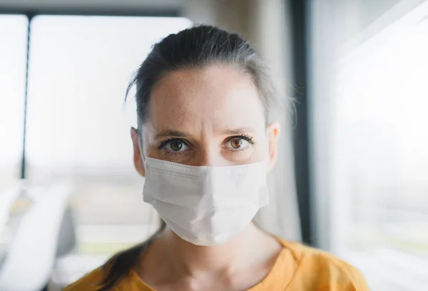 Vrouw met gezichtsmasker binnenshuis, corona virus en quarantaine concept. — Stockfoto