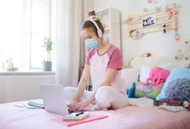 Yatağında dizüstü bilgisayarı olan genç kız öğrenci, online ders konsepti..