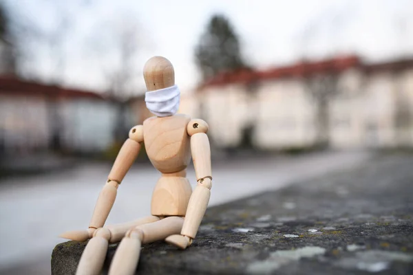 Sad wooden mannequin with face mask in town, corona virus and lockdown concept. — Stock Photo, Image