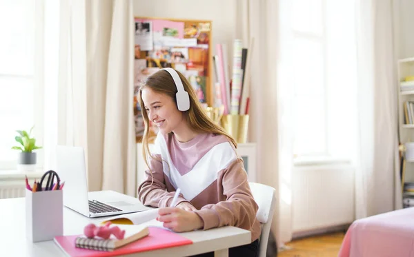 Ung kvinnlig student sitter vid bordet, med bärbar dator när du studerar. — Stockfoto