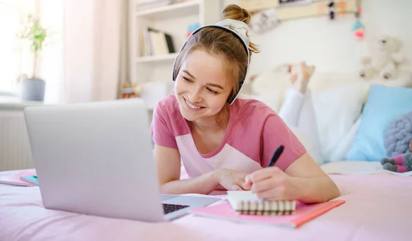 Jonge studente met laptop op bed, online lesconcept. — Stockfoto