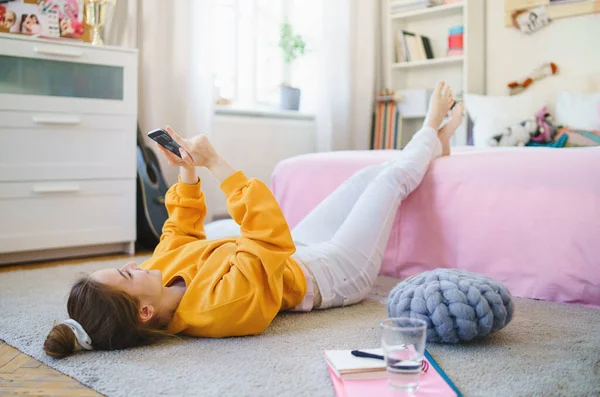 Chica joven con teléfono inteligente en el suelo en casa, haciendo videollamada . — Foto de Stock