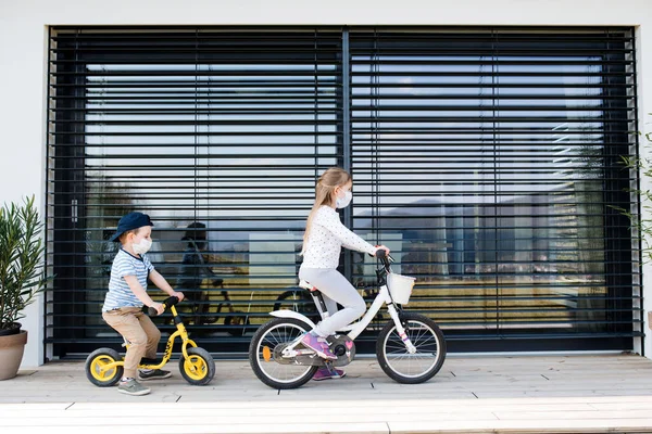 Kleine Mädchen und Jungen mit Fahrrädern im Freien zu Hause. Coronavirus und Quarantäne-Konzept. — Stockfoto