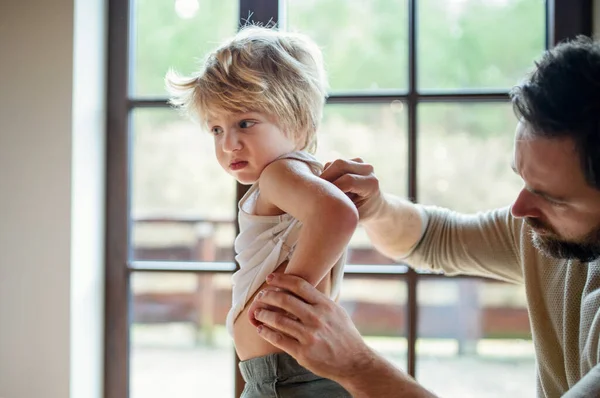 Father with small sick unhappy son indoors at home, checking his back. — Stock Photo, Image