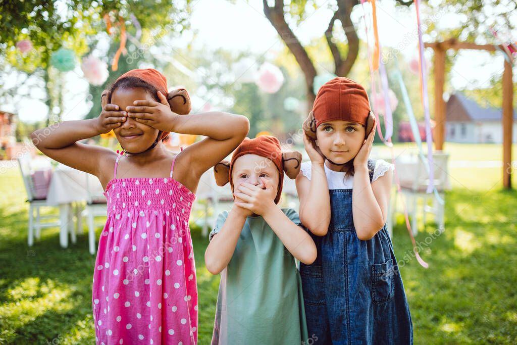 Small children with masks outdoors on garden party in summer, playing.