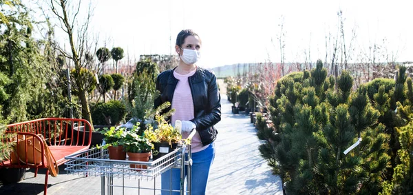 Młoda kobieta z maską na zewnątrz zakupy w centrum ogrodu, koncepcja wirusa Corona. — Zdjęcie stockowe