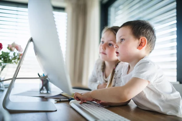 Menina pequena e menino usando computador dentro de casa. Conceito de vírus Corona e quarentena . — Fotografia de Stock