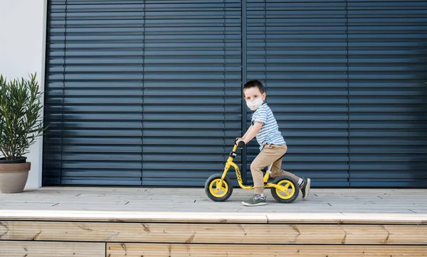 Menino pequeno com bicicleta ao ar livre em casa. Conceito de vírus Corona e quarentena . — Fotografia de Stock