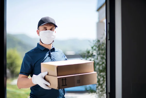 Mensajero con máscara facial entregando paquete, virus corona y concepto de cuarentena . — Foto de Stock