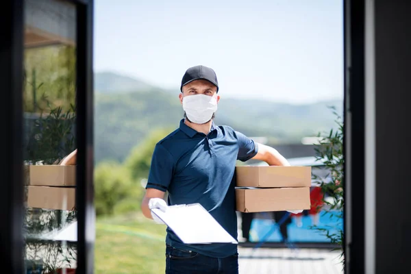 Kurir med ansiktsmask som levererar paket, koronavirus och karantänkoncept. — Stockfoto
