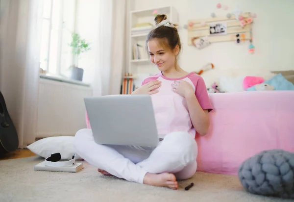 Jong meisje met laptop zittend op de vloer, ontspannen tijdens quarantaine. — Stockfoto