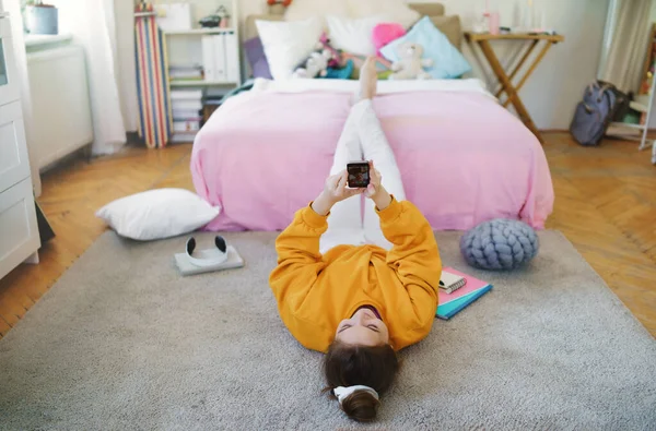 Giovane ragazza con smartphone sul pavimento a casa, fare videochiamate . — Foto Stock