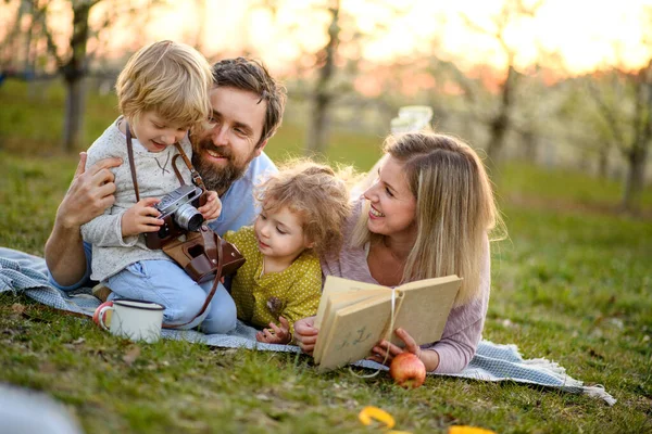 Famille et petits enfants avec caméra et réserver à l'extérieur dans la nature printanière, au repos . — Photo