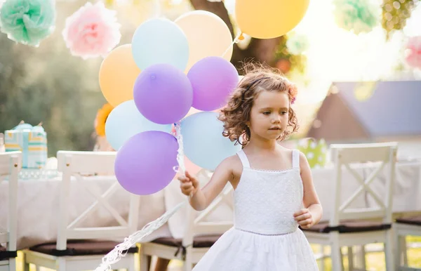 Retrato de menina pequena brincando com balões ao ar livre na festa do jardim no verão . — Fotografia de Stock