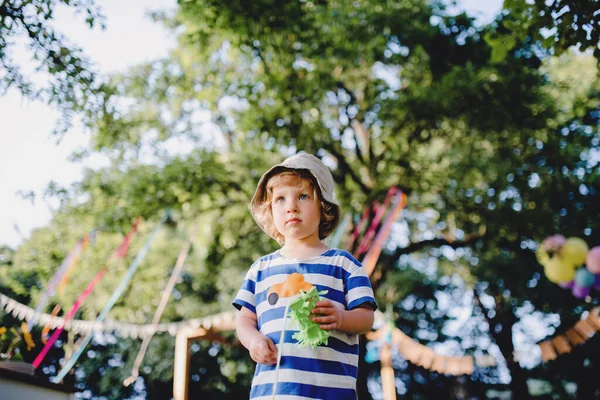 Low angle view of small boy standing outdoors on garden party, playing. — Stock Photo, Image