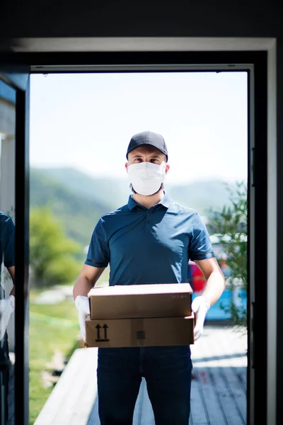 Kurir med ansiktsmask som levererar paket, koronavirus och karantänkoncept. — Stockfoto