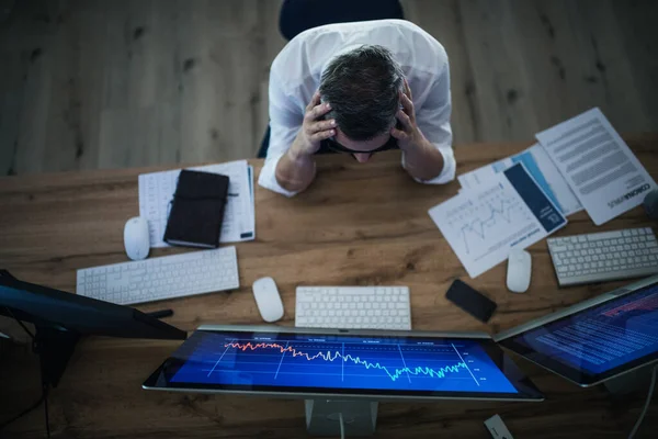Bovenaanzicht van gefrustreerde zakenman met computer aan het werk aan het bureau. Begrip financiële crisis. — Stockfoto