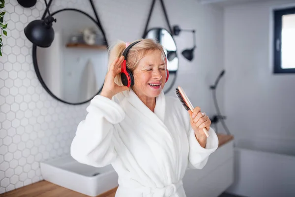 Porträt einer Seniorin mit Kopfhörer und Bademantel zu Hause. — Stockfoto