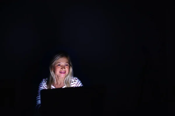 夜遅くに自宅で働いているラップトップを持つシニア女性. — ストック写真