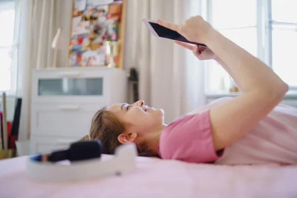 Chica joven con la tableta en la cama, relajarse durante la cuarentena. Copiar espacio . — Foto de Stock