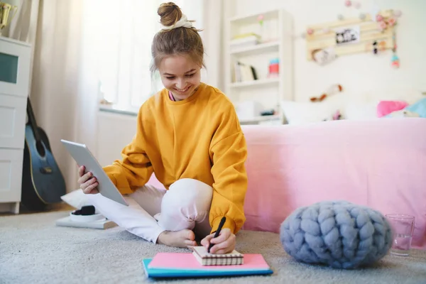 Jeune fille avec tablette assise sur le sol, étudiant pendant la quarantaine . — Photo