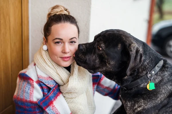 Junge Frau entspannt sich draußen vor der Haustür mit Hund. — Stockfoto