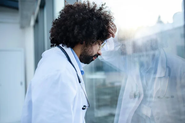 Worried and tired doctor standing in hospital, corona virus concept. — Stock Photo, Image