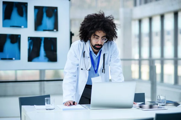 Portrét seriózního mužského lékaře stojícího v nemocnici, používajícího notebook. — Stock fotografie