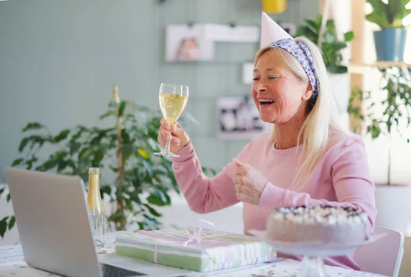 Senior woman with laptop indoors at home, celebrating distance birthday. — Stock Photo, Image