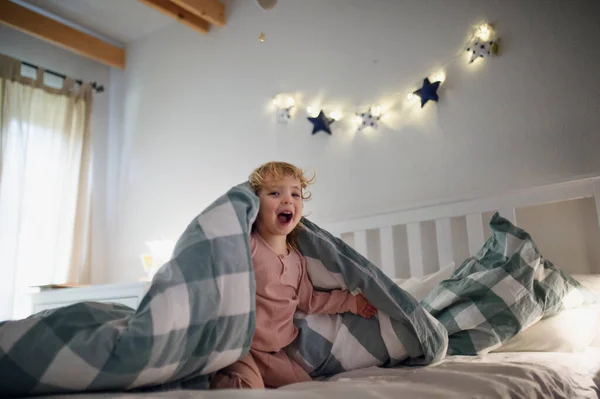 Pequeña niña jugando en la cama en casa, divirtiéndose . — Foto de Stock