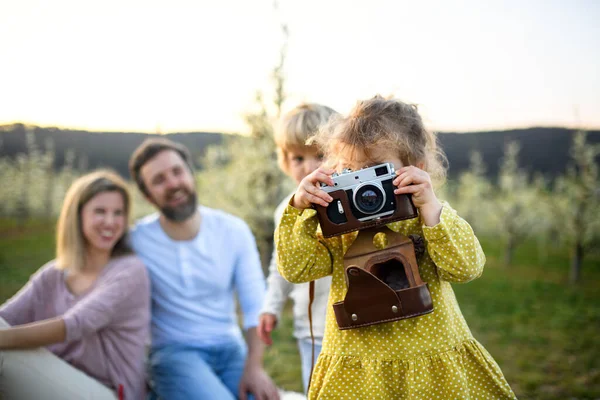 Rodina s malými dětmi sedící venku na jaře přírody, fotografování. — Stock fotografie