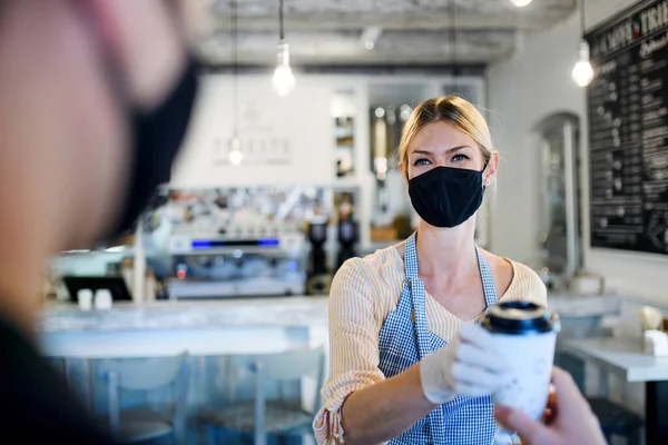 Женщина в маске обслуживает клиента, магазин открыт после карантина . — стоковое фото